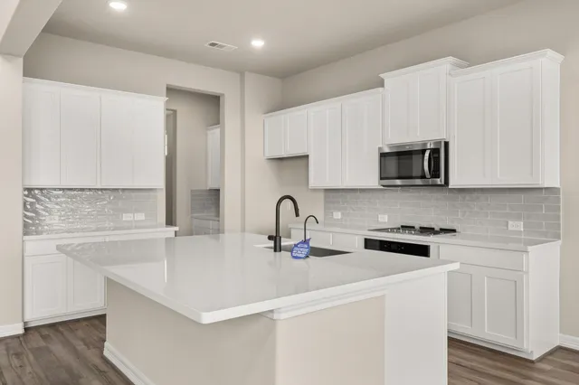 a kitchen with stainless steel appliances granite countertop a sink a stove a microwave a counter space and cabinets
