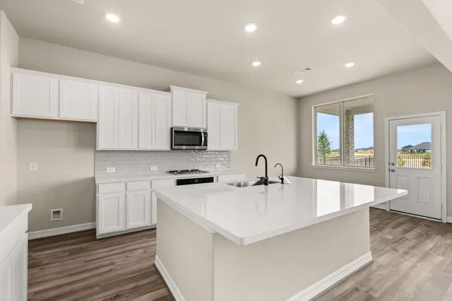 a large white kitchen with wooden floor