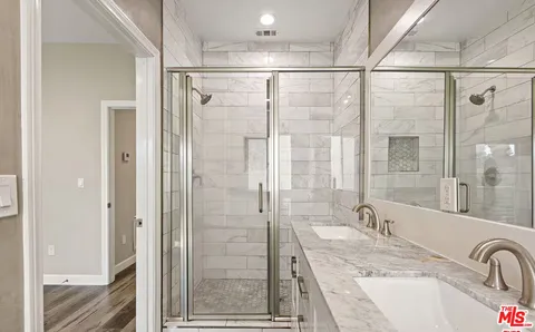 a bathroom with a granite countertop sink a mirror a shower and vanity