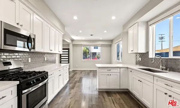 a kitchen with stainless steel appliances a sink dishwasher a stove and a microwave oven with wooden floor