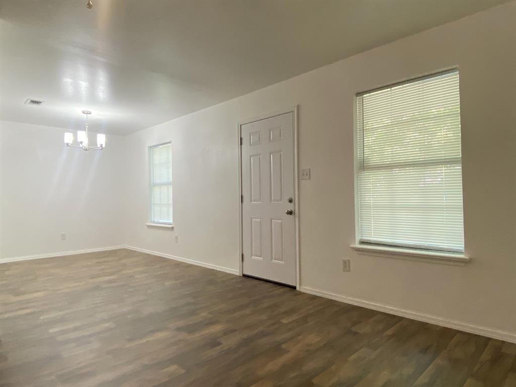 505 Red Springs Avenue Mount Pleasant, TX 75455 - Photo 2 of 9 Unfurnished room featuring dark wood-type flooring and a chandelier