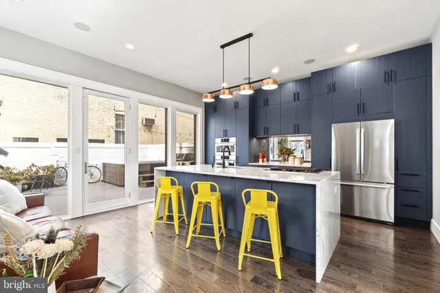 a kitchen with stainless steel appliances granite countertop a refrigerator a sink dishwasher a dining table and chairs with wooden floor