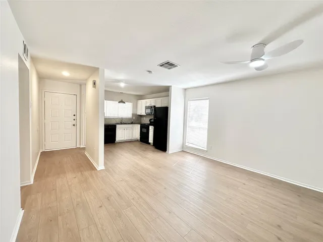 a view of a big room with wooden floor and windows