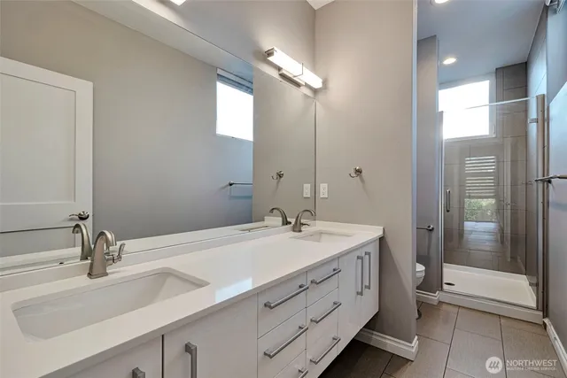 a bathroom with a double vanity sink mirror and shower
