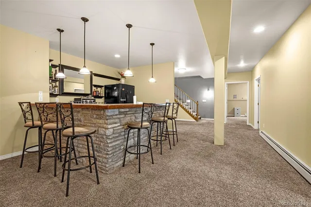 a view of a room with kitchen island stainless steel appliances kitchen island granite countertop chairs and a view of living room