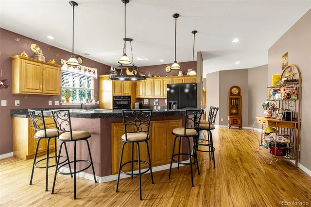 a dining area with stainless steel appliances granite countertop furniture wooden floor and a kitchen view