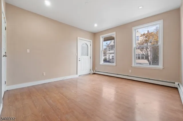 a view of an empty room with a window and wooden floor