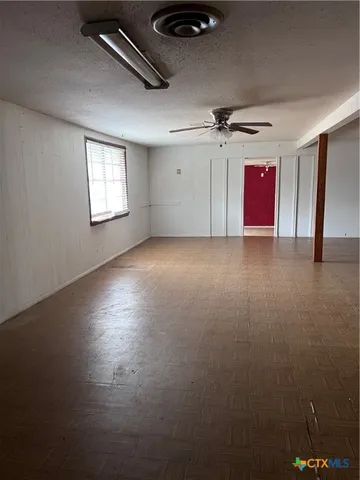 an empty room with windows and ceiling fan
