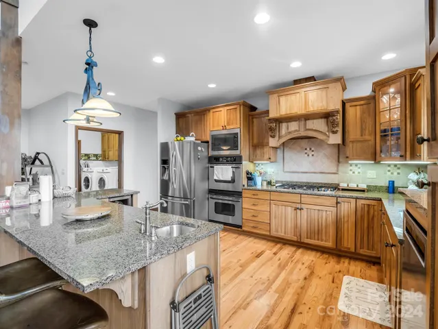 a kitchen with stainless steel appliances granite countertop a refrigerator stove top oven dining table and chairs