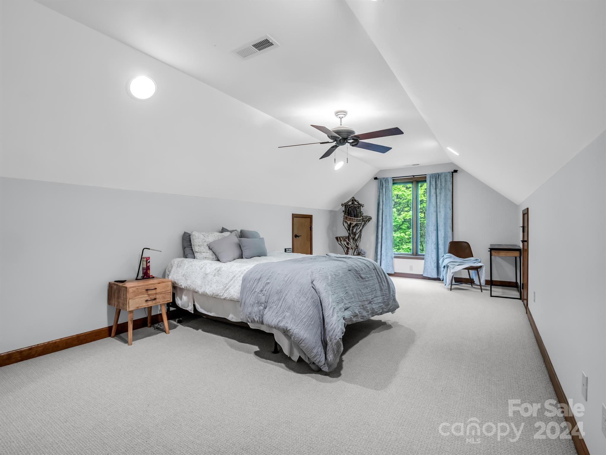 428 Devils Hole Road, Unit 14 Rosman, NC 28772 - Photo 30 of 47 a spacious bedroom with a bed and a chandelier