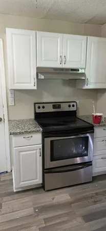a kitchen with granite countertop white cabinets and stainless steel appliances