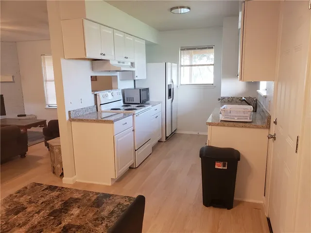 a kitchen with granite countertop a sink cabinets and wooden floor