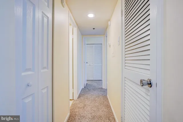 a view of a hallway with closet and a bathroom