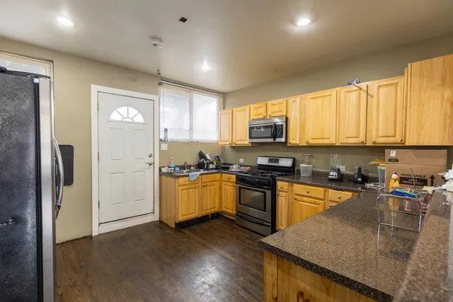 a kitchen with granite countertop a stove top oven a sink dishwasher a refrigerator and cabinets with wooden floor