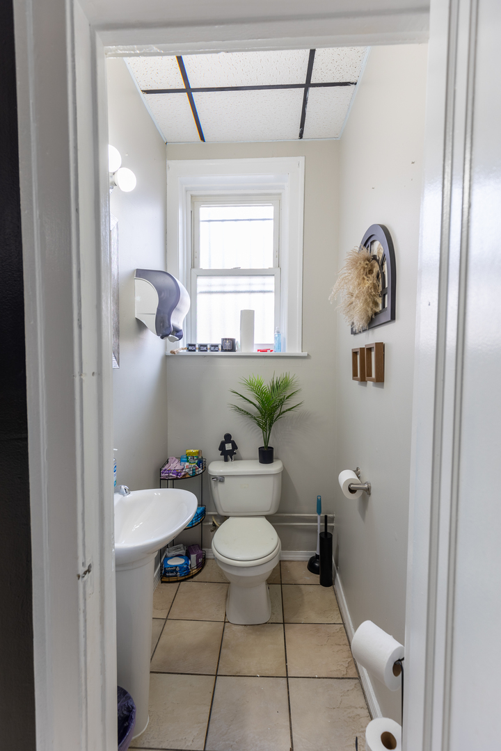 5820-24 West Roosevelt Road Chicago, IL 60644 - Photo 10 of 25 a bathroom with a toilet a sink and a mirror