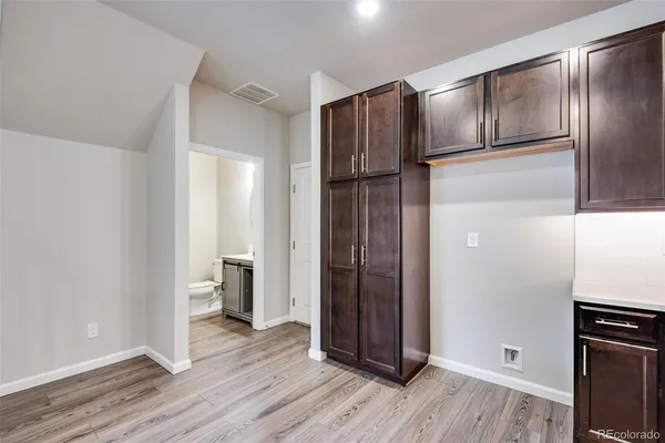 a view of an empty room with wooden floor and a kitchen