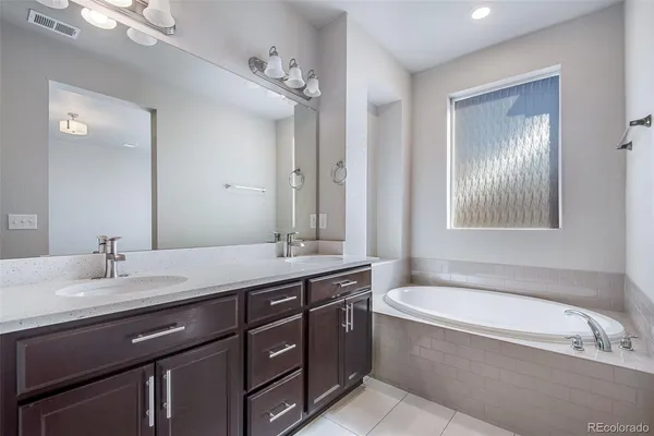 a bathroom with a granite countertop bathtub sink double and mirror