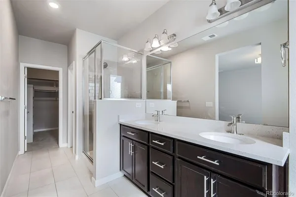 a spacious bathroom with a double vanity sink a mirror and a shower