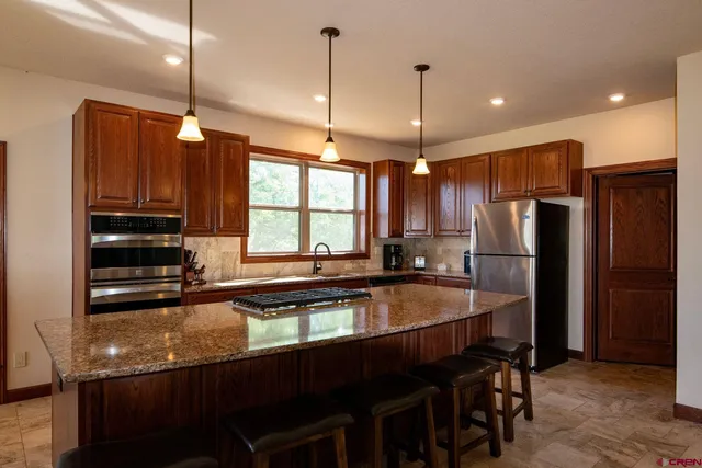 a kitchen with stainless steel appliances granite countertop a sink refrigerator and cabinets
