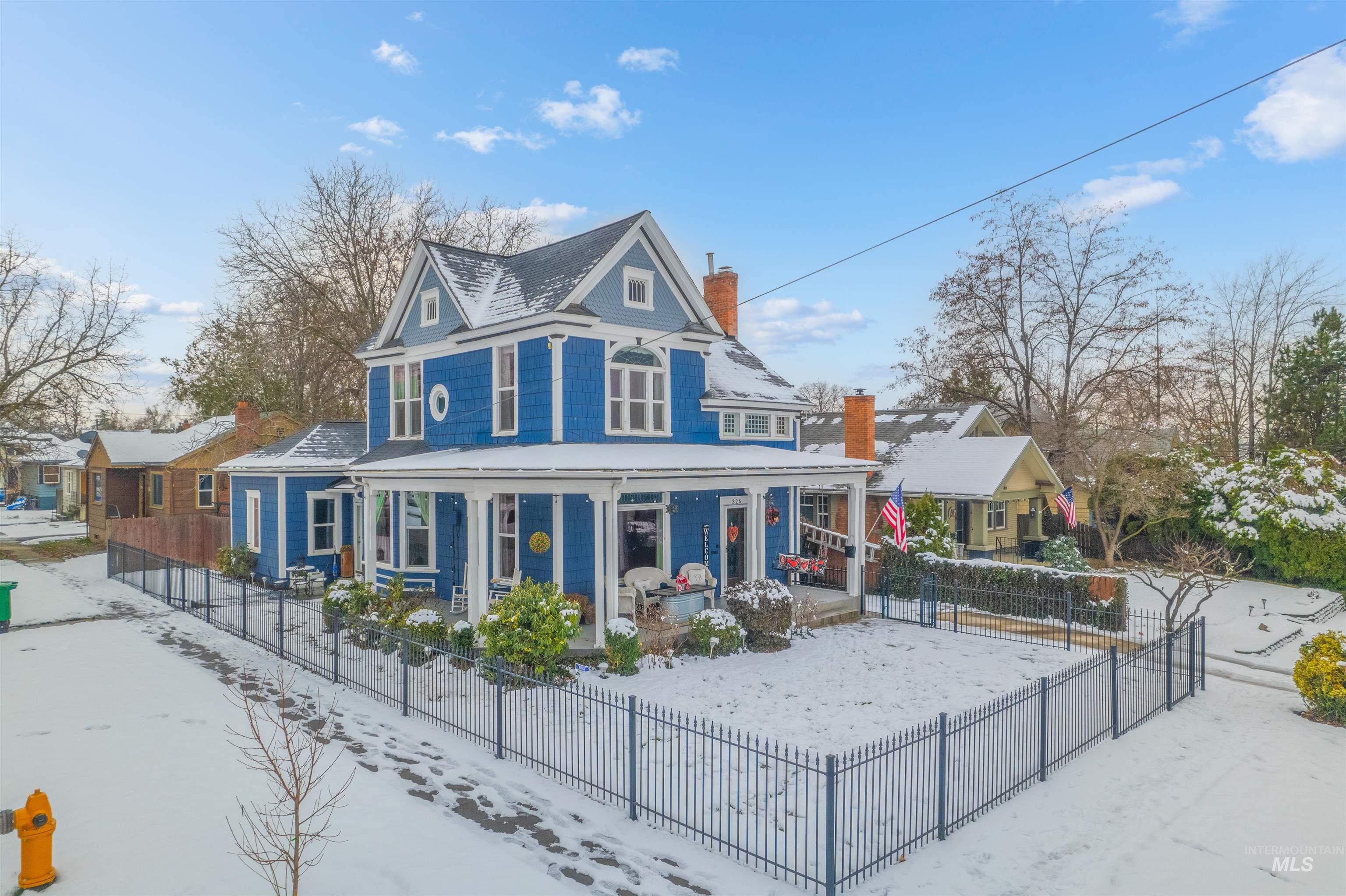 Victorian house featuring a fenced front yard, a porch, and a chimney
