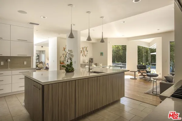 a kitchen with stainless steel appliances a stove a sink a microwave a dining table and chairs with wooden floor