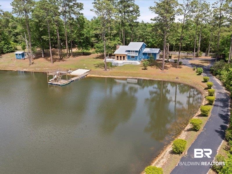 3160 Old Castleberry Road Brewton, AL 36426 - Photo 26 of 36 Waterfront property featuring a blue-sided residence with white trim, a multi-level deck, and a private dock on a sizable pond