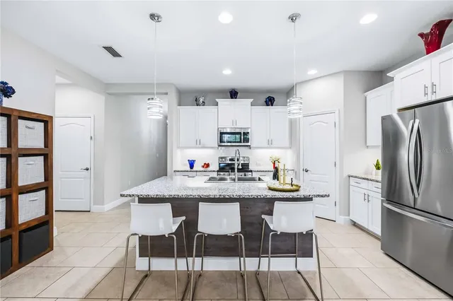 a kitchen with stainless steel appliances kitchen island granite countertop a table chairs and a refrigerator