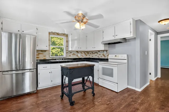 a kitchen with stainless steel appliances granite countertop a stove a refrigerator and a granite counter tops with white cabinets