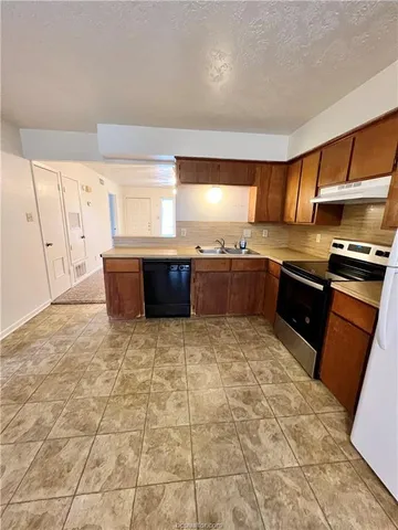 a large kitchen with granite countertop a stove a sink dishwasher and a refrigerator