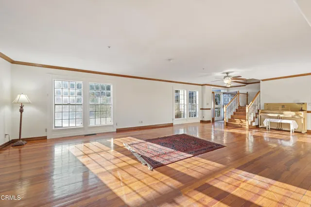 a view of empty room with wooden floor and fan