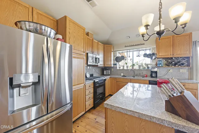 a kitchen with stainless steel appliances granite countertop a refrigerator a stove and a sink