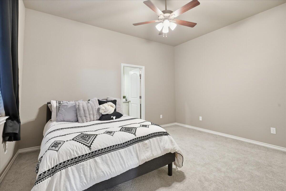 7612 59th Street Lubbock, TX 79407 - Photo 18 of 42 a bedroom with a large bed and a chandelier