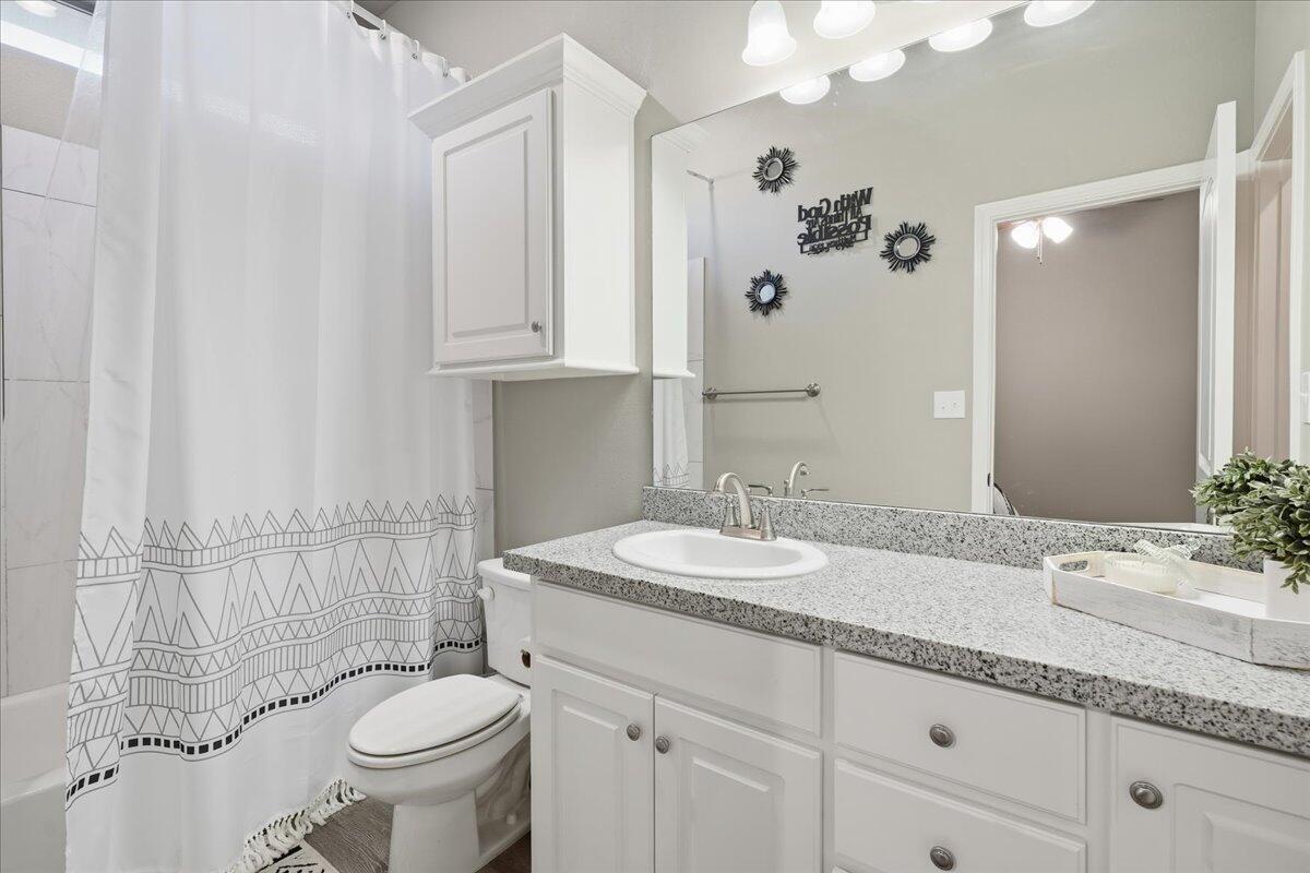 7612 59th Street Lubbock, TX 79407 - Photo 20 of 42 a bathroom with a sink and mirror with toilet