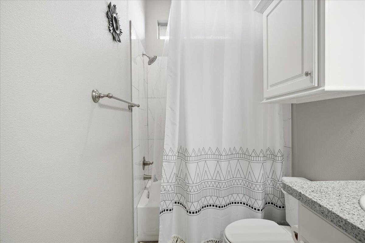 7612 59th Street Lubbock, TX 79407 - Photo 21 of 42 a bathroom with a granite countertop toilet and a shower