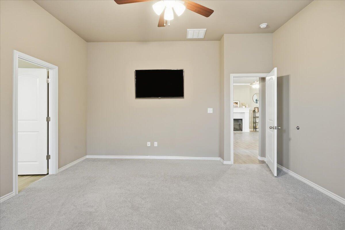 7612 59th Street Lubbock, TX 79407 - Photo 25 of 42 an empty room with kitchen view and a chandelier fan