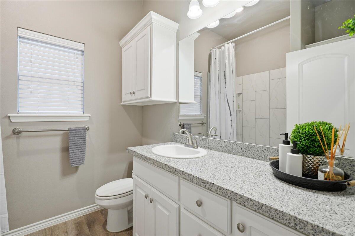 7612 59th Street Lubbock, TX 79407 - Photo 36 of 42 a bathroom with a granite countertop sink a toilet and a mirror
