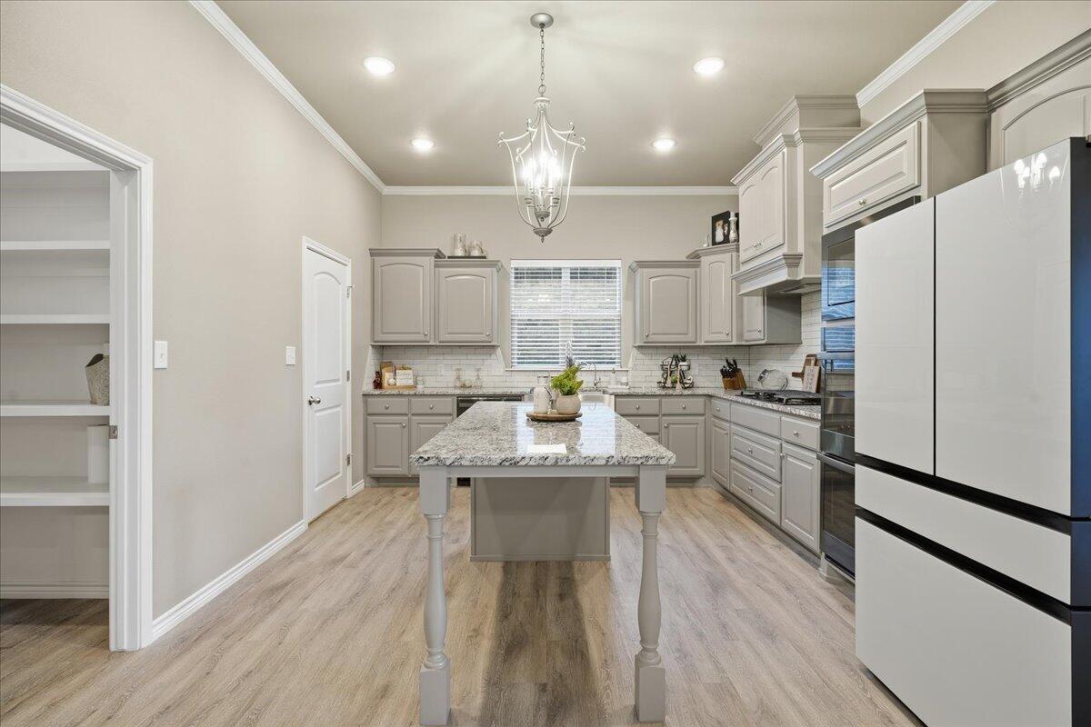 7612 59th Street Lubbock, TX 79407 - Photo 10 of 42 a kitchen with kitchen island white cabinets and stainless steel appliances
