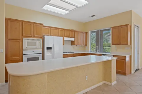 a kitchen with stainless steel appliances granite countertop a refrigerator a sink a stove and a refrigerator