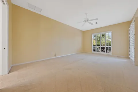 an empty room with windows and ceiling fan