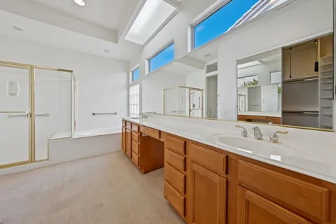 a spacious bathroom with a double vanity sink a mirror and a bathtub