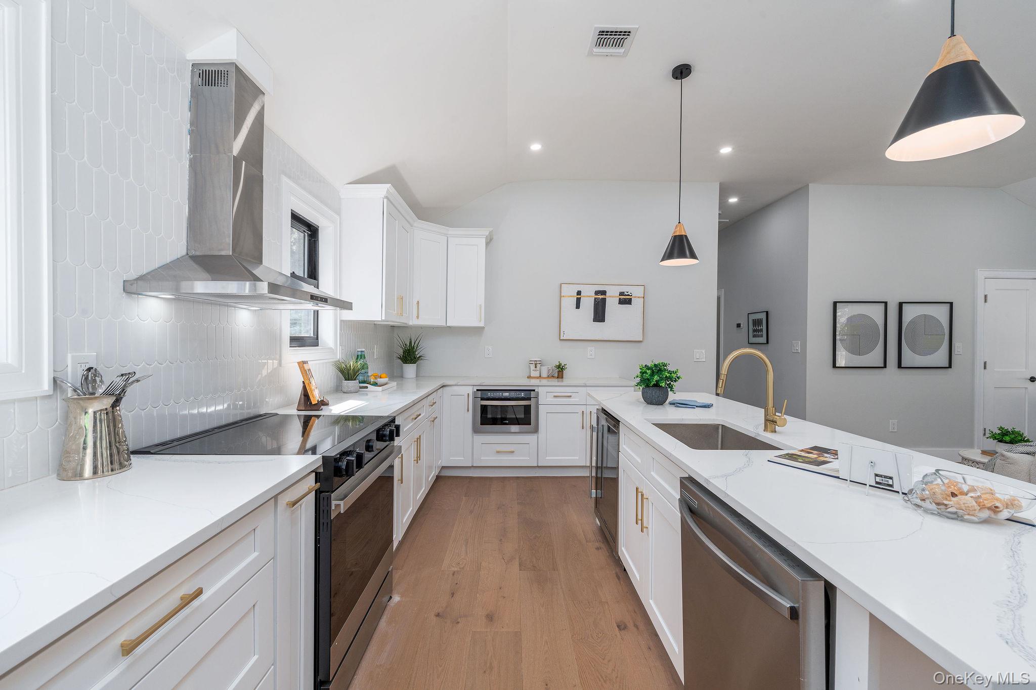 3420 Rocky Point Road East Marion, NY 11939 - Photo 10 of 34 Kitchen with stainless steel appliances, hanging light fixtures, wall chimney exhaust hood, backsplash, and light wood finished floors