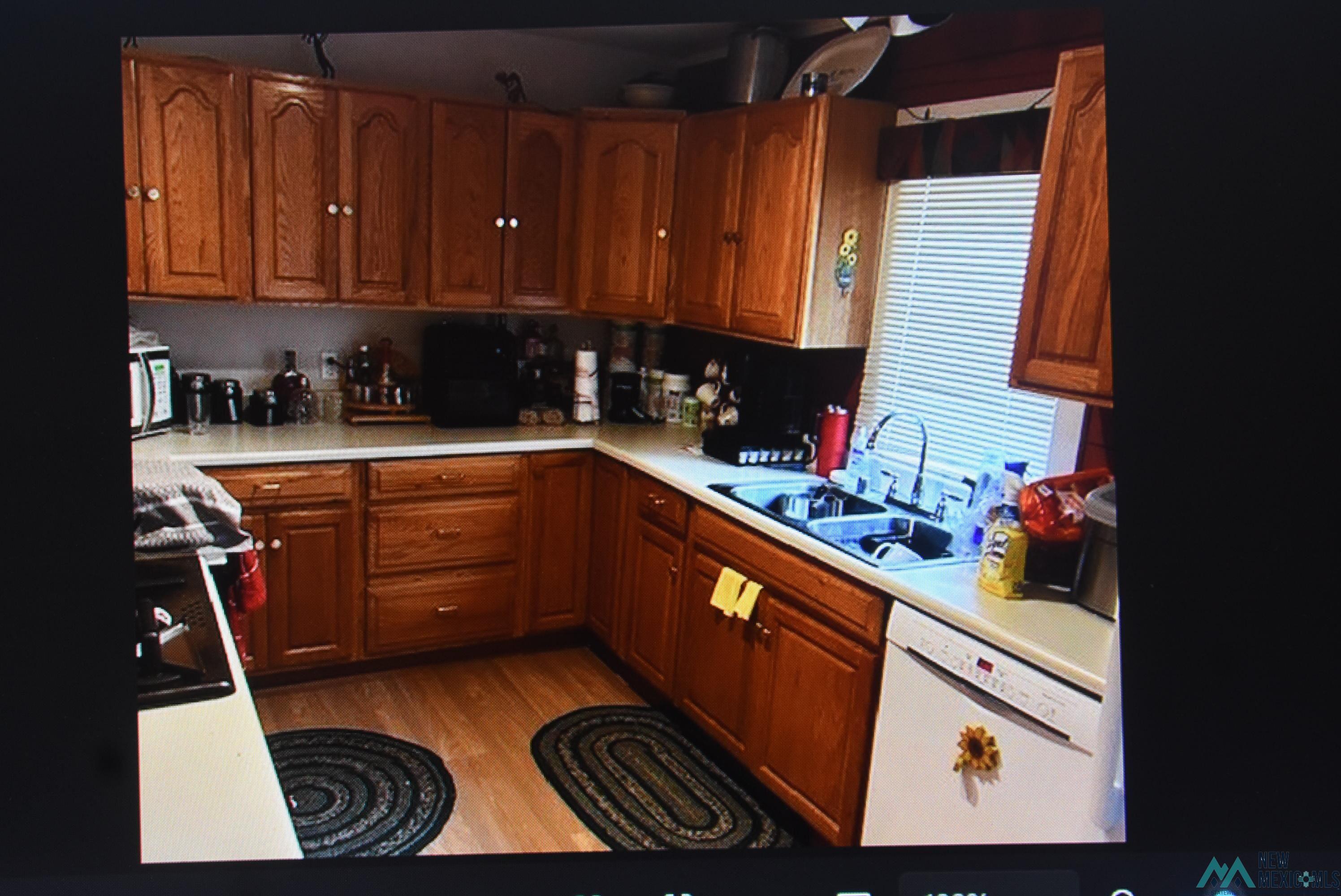 27 Golf Drive Rociada, NM 87742 - Photo 10 of 10 Kitchen with brown cabinets, light countertops, dishwasher, light wood-style flooring, and black range