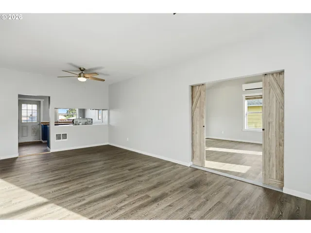 a view of an empty room and window with wooden floor