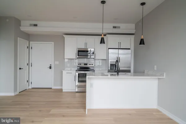 a kitchen with stainless steel appliances granite countertop a sink a stove a refrigerator and white cabinets