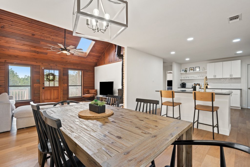 201 Raincloud Road Wimberley, TX 78676 - Photo 11 of 40 Dining space featuring lofted ceiling, light wood finished floors, wood walls, ceiling fan, and a skylight