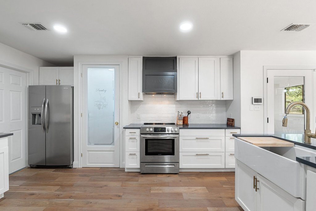 201 Raincloud Road Wimberley, TX 78676 - Photo 13 of 40 Kitchen featuring stainless steel appliances, white cabinetry, light wood-style floors, backsplash, and recessed lighting