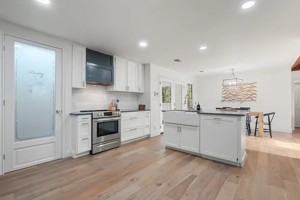 a kitchen with stainless steel appliances white cabinets and a wooden floors