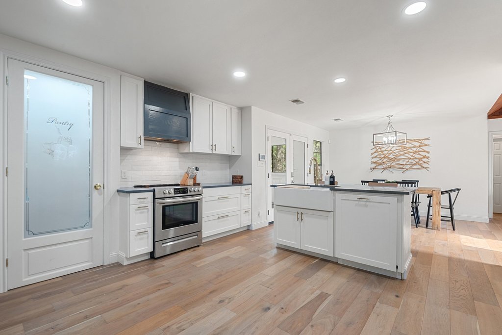 201 Raincloud Road Wimberley, TX 78676 - Photo 14 of 40 Kitchen featuring stainless steel electric stove, dark countertops, white cabinets, decorative backsplash, and light wood-style floors