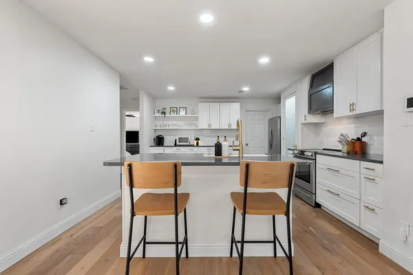 a kitchen with stainless steel appliances kitchen island granite countertop a dining table chairs and sink