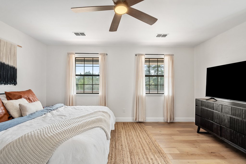 201 Raincloud Road Wimberley, TX 78676 - Photo 19 of 40 Bedroom with light wood-style floors, a ceiling fan, and multiple windows